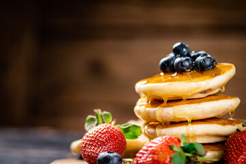 Wall Mural - A pile of pancakes with fresh berries and honey on the table. 