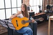 © Krakenimages.com - Young beautiful woman playing classic guitar at music studio pointing thumb up to the side smiling happy with open mouth