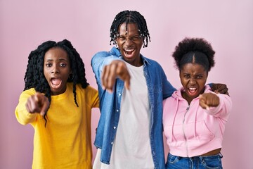 Poster - Group of three young black people standing together over pink background pointing displeased and frustrated to the camera, angry and furious with you