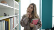 © Krakenimages.com - Young blonde woman student holding books with doubt expression at library university