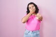 © Krakenimages.com - Young hispanic woman standing over pink background laughing at you, pointing finger to the camera with hand over mouth, shame expression