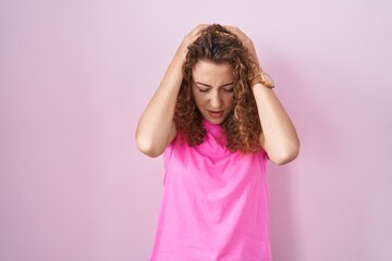 Poster - Young caucasian woman standing over pink background suffering from headache desperate and stressed because pain and migraine. hands on head.