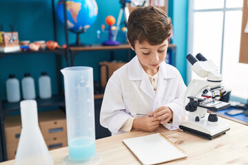 Poster - Adorable hispanic boy student looking notebook at laboratory classroom