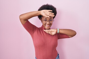 Sticker - Beautiful african woman with curly hair standing over pink background smiling cheerful playing peek a boo with hands showing face. surprised and exited