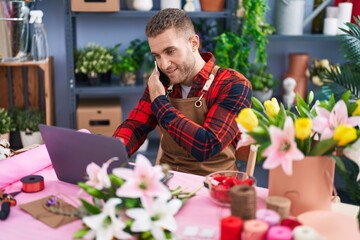 Sticker - Young caucasian man florist talking on smartphone using laptop at flower shop