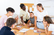 © JackF - Diverse people sitting at desk during language courses in classroom. Senior and young people listening to native speaker teacher.