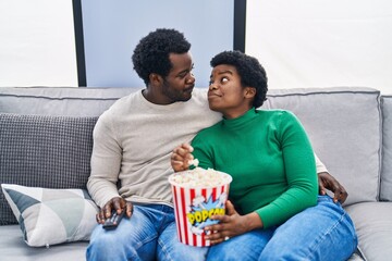 Poster - African american man and woman couple watching movie eating popcorn at home