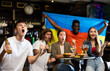 © JackF - Happy international sport fans waving flag Ukraine during football match, drinking beer, eating chips in the pub