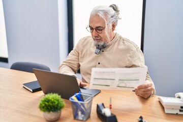 Wall Mural - Middle age grey-haired man business worker using laptop reading document at office