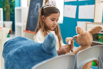 Sticker - Adorable blonde girl wearing princess crown playing with rabbit doll at kindergarten