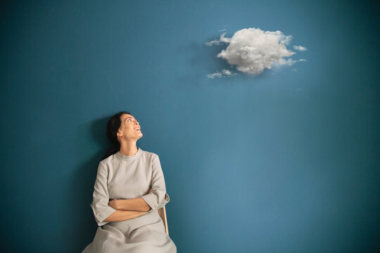 woman observes astonished surreal cloud flying in her room, abstract concept