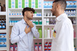 © Krakenimages.com - Two hispanic men pharmacist speaking to client suffering for throat pain at pharmacy