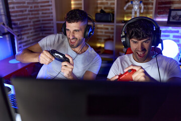 Poster - Two hispanic men streamers playing video game using joystick at gaming room