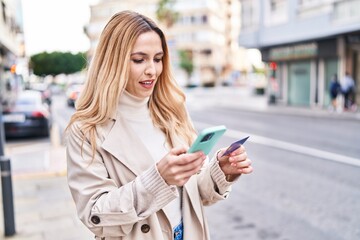 Canvas Print - Young blonde woman using smartphone and credit card at street