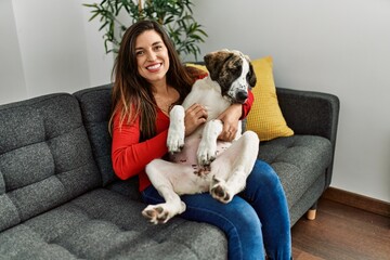 Poster - Young woman hugging dog sitting on sofa at home