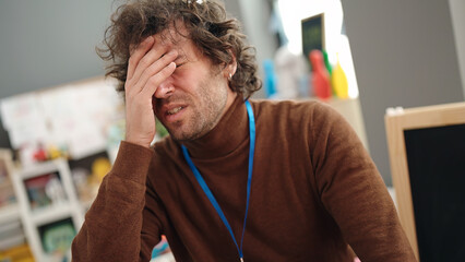 Canvas Print - Young hispanic man preschool teacher stressed at kindergarten