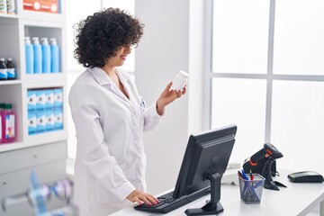 Canvas Print - Young middle east woman pharmacist using computer holding pills at pharmacy