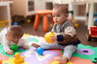 © Krakenimages.com - Two adorable toddlers playing with balls sitting on floor at kindergarten