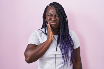 Poster - Young african woman standing over pink background touching mouth with hand with painful expression because of toothache or dental illness on teeth. dentist