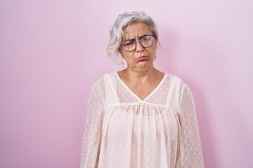 Poster - Middle age woman with grey hair standing over pink background depressed and worry for distress, crying angry and afraid. sad expression.