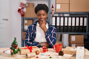 Poster - African american woman working at small business doing christmas decoration looking confident at the camera with smile with crossed arms and hand raised on chin. thinking positive.