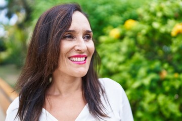 Wall Mural - Young beautiful hispanic woman smiling confident looking to the side at park