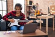 © Krakenimages.com - African american woman musician having online electrical guitar lesson at music studio