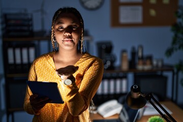 Canvas Print - African american woman with braids working at the office at night with tablet looking at the camera blowing a kiss with hand on air being lovely and sexy. love expression.