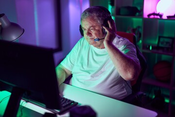 Poster - Middle age grey-haired man streamer playing video game using computer at gaming room