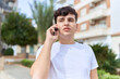 © Krakenimages.com - Non binary man talking on smartphone with worried expression at park