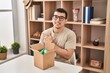 © Krakenimages.com - Young arab man with open gift in cardboard box smiling cheerful pointing with hand and finger up to the side