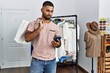 © Krakenimages.com - Young arab man using smartphone holding shopping bags at clothing store