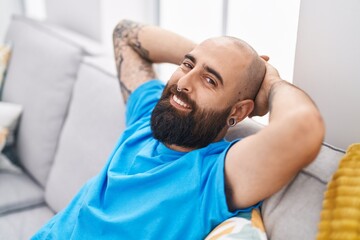 Canvas Print - Young bald man relaxed with hands on head sitting on sofa at home