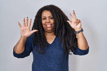 Sticker - Plus size hispanic woman standing over white background showing and pointing up with fingers number eight while smiling confident and happy.