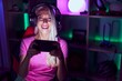 © Krakenimages.com - Young blonde woman streamer playing video game by smartphone at gaming room
