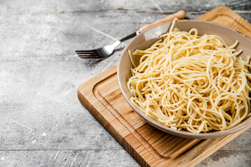 Canvas Print - Full bowl with boiled spaghetti on a cutting board. 