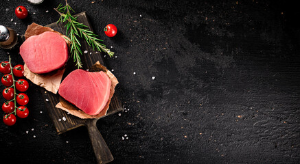 Wall Mural - Raw tuna on a cutting board with tomatoes and rosemary. 