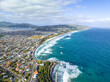 High angle aerial drone view of St Clair, a beachside suburb of Dunedin, second-largest city in the South Island of New Zealand. Dunedin city in the background. Hot water salt rock pool in foreground.