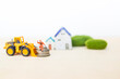 Miniature worker on coin stack with front loader truck over blurred house background, property investment, real estate business