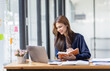 © David - Stylish asian girl works in home office with laptop, makes notes, report Financial Accounting concept.
