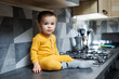 © DSMT - A little boy 1 year old in yellow clothes is sitting in the kitchen on the table. Portrait of a cute one-year-old boy.