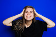 © DSMT - Happy beautiful woman without makeup in a black t-shirt showing different emotions on a blue background. Natural female beauty without cosmetics, naturalness. The concept of beauty