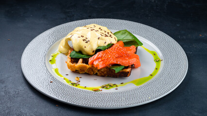 Wall Mural - Breakfast plate waffles with poached egg, salmon, red caviar, spinach and sauce.