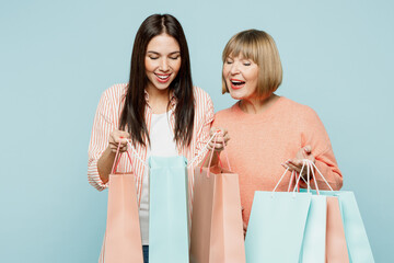 Happy elder mom with young adult daughter two women wear casual clothes hold open paper package bags after shopping isolated on plain light pastel blue background. Black Friday sale buy day concept.