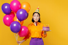 Happy Fun Amazed Young Woman In Casual Clothes Hat Celebrating Hold Bunch Of Colorful Air Balloons Cake With Candles Blow Pipe Isolated On Plain Yellow Background Birthday 8 14 Holiday Party Concept