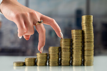 woman with her fingers going uphill on stacks of gold coins.