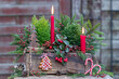rote Kerzen, Scheinbeere und Koniferen in alter Ziegelform als Weihnachtsdekoration