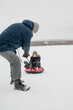 © Westend61 - Father pulling son sitting on inflatable sled in snow