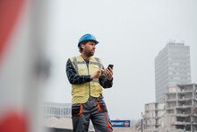 Smiling Mature Worker With Smart Phone At Construction Site