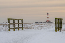Germany, Schleswig-Holstein, Westerhever, Snow-covered Field At Dusk With Westerheversand Lighthouse In Background
